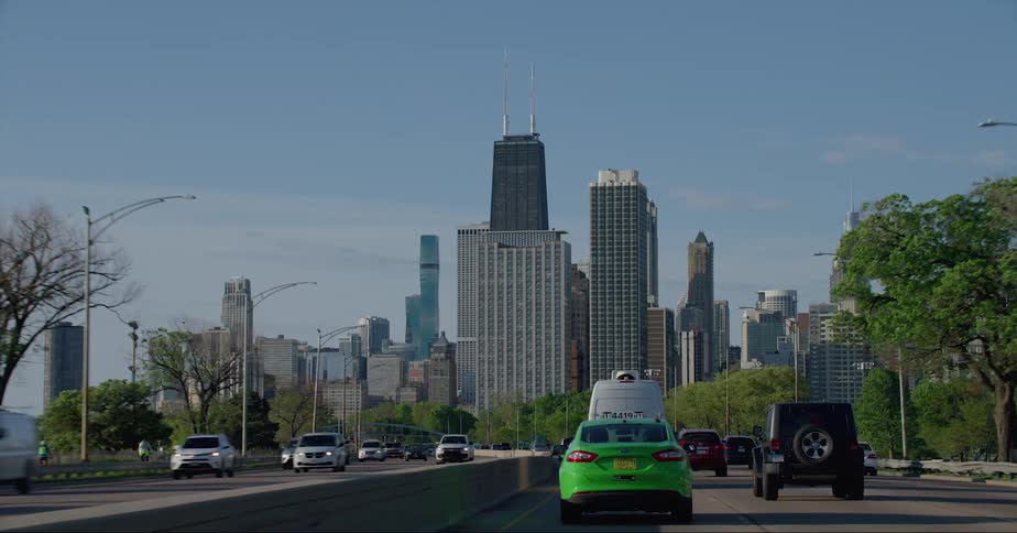 Vehicles driving on a freeway heading towards the chicago skyline at daytime