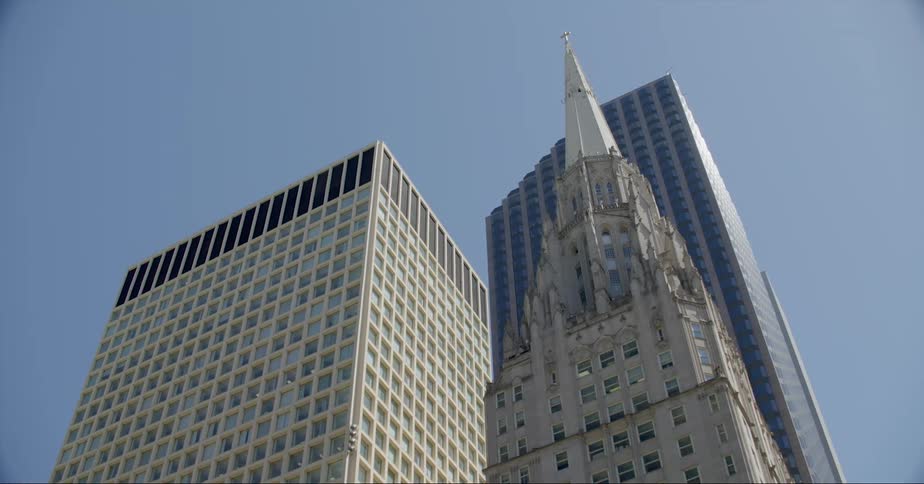 A historic stone skyscraper sits behind a modern steel skyscraper downtown