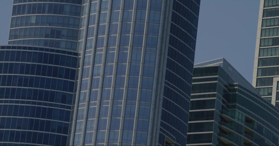 City skyscrapers loom larger and large as trees are passed