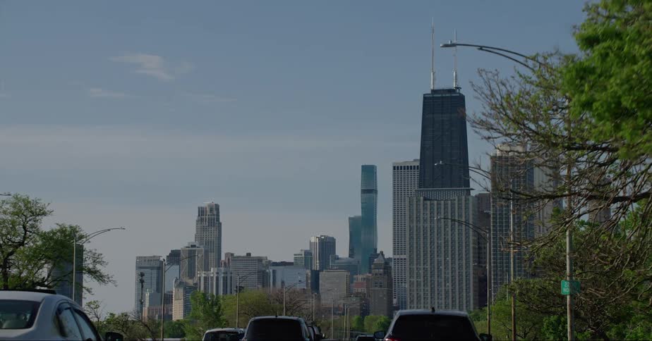 Traffic moves to and from city skyline under a slightly clouded sky