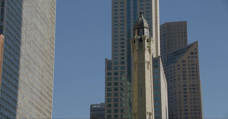 A gothic style clock tower sits between tall modern skyscrapers