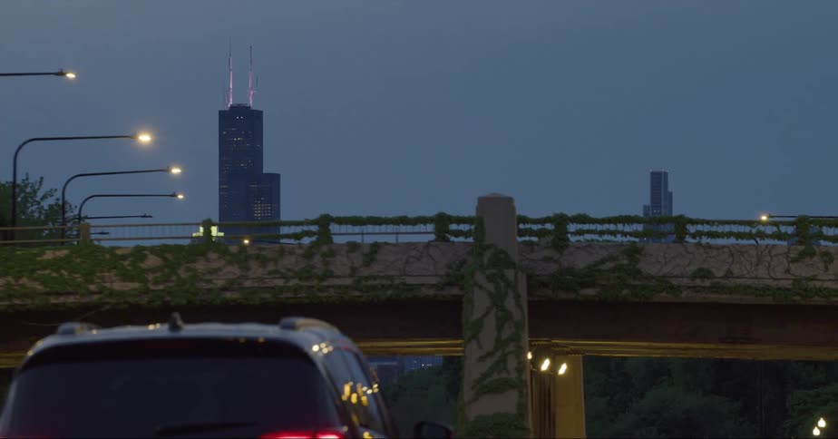 Cars traveling on an urban road with skyscrapers in the distance
