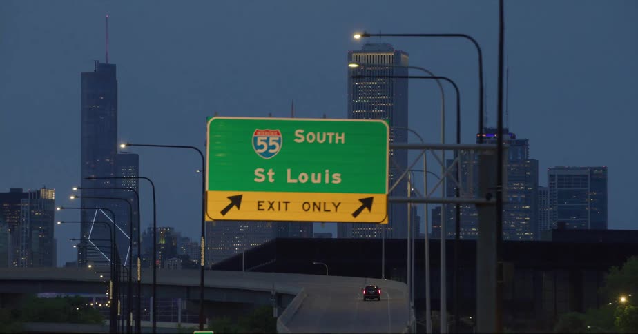 Street signs and a car driving in a city with high rise office buildings