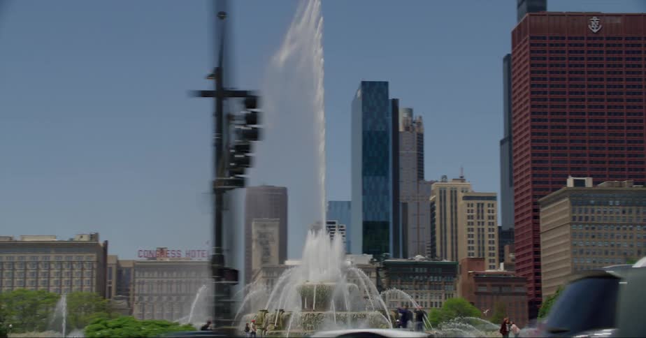Water spouts rains down over fountain at park with downtown skyscrapers in the background