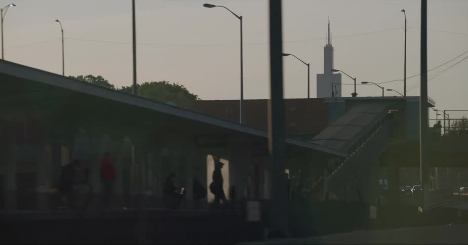 People wait at a train station in a city