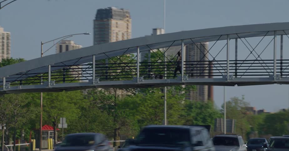 Distant skyscrapers and high rise buildings seen from vehicle driving on highway passing under overpass