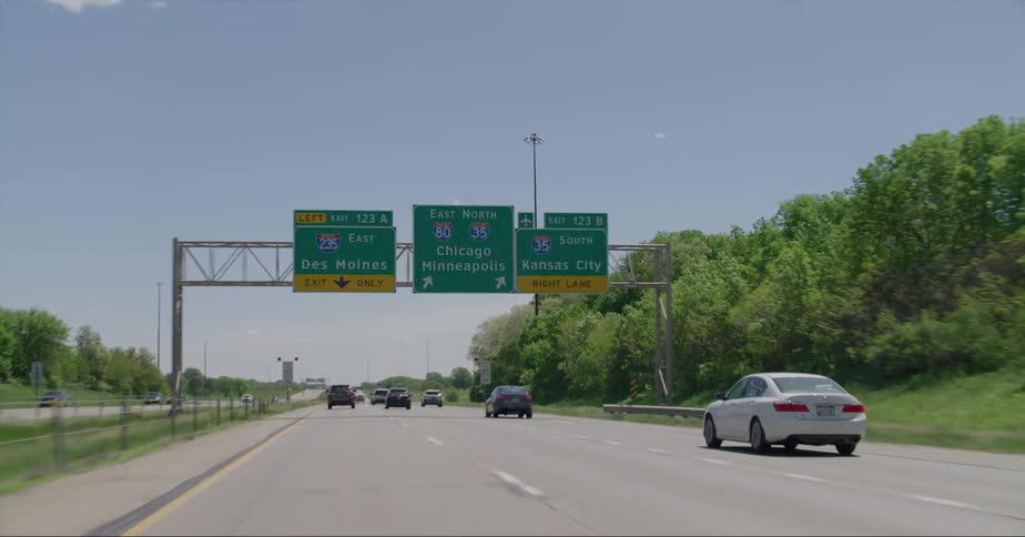 Cars traveling on a multi lane highway with exit signs for chicago and minneapolis