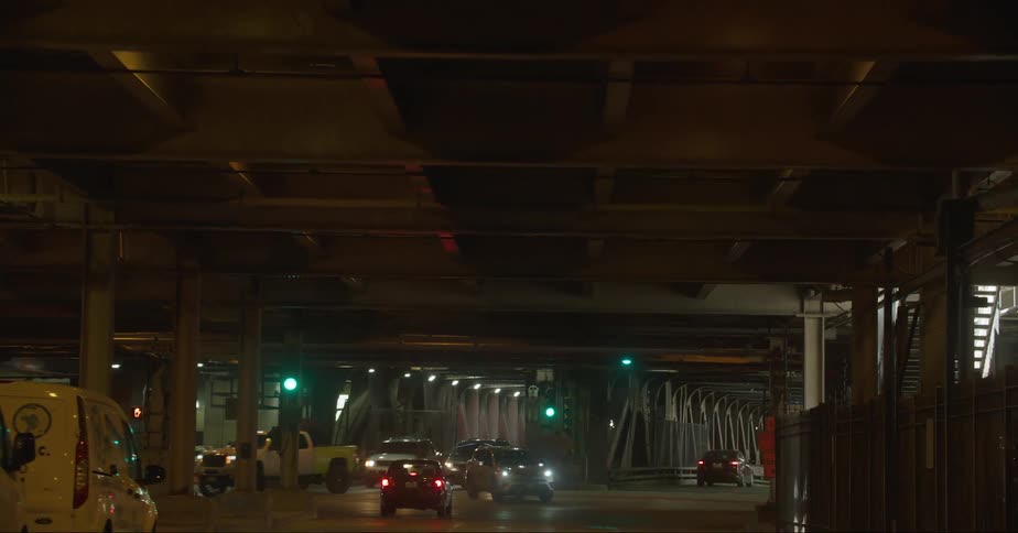 Headlights shine as automobiles travel through a dark tunnel