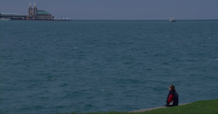 A person sits on the shore and looks out at the ocean