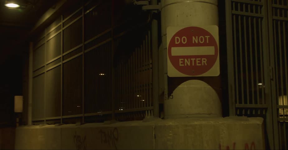 A do not enter sign is at the exit of a tunnel leading out of a parking garage as traffic moves out