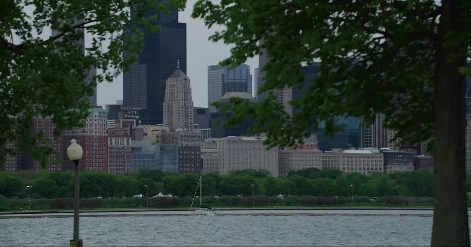 A boat sails in a river with a city skyline behind it