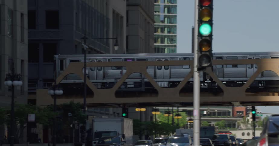 The elevated train travels over a chicago city street between buildings