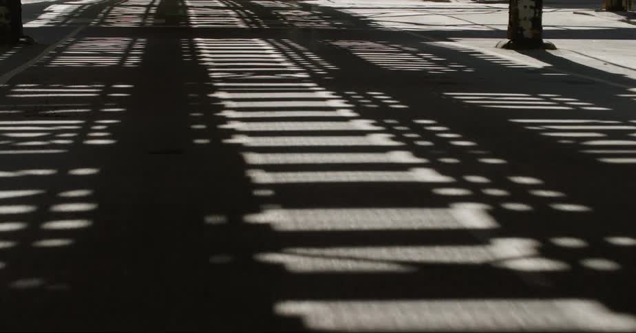 Sunlight shines through a bridge and casts shadows on the road below