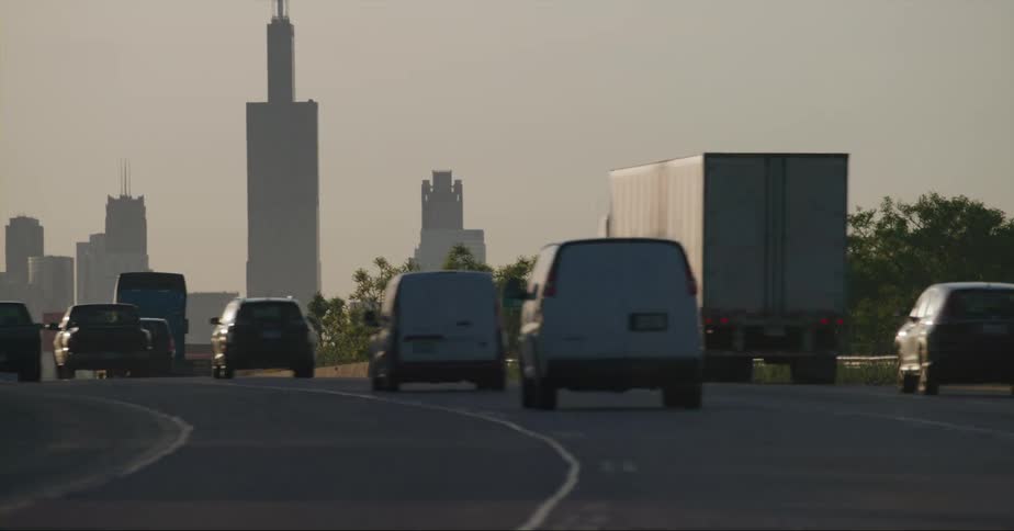Heavy vehicle traffic heads down a highway toward downtown