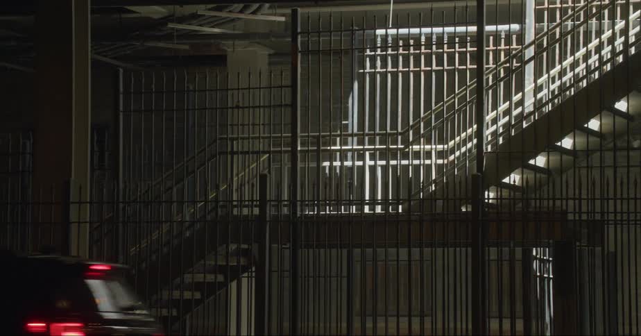 Subterranean staircase enclosed by an iron fence next to a road on a tunnel