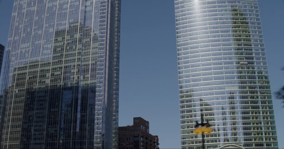 The chicago city skyline is reflected on the facade of the river point skyscraper on a bright blue sky day