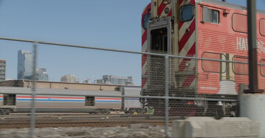 Freight train arrives at a station next to the city skyline at daytime