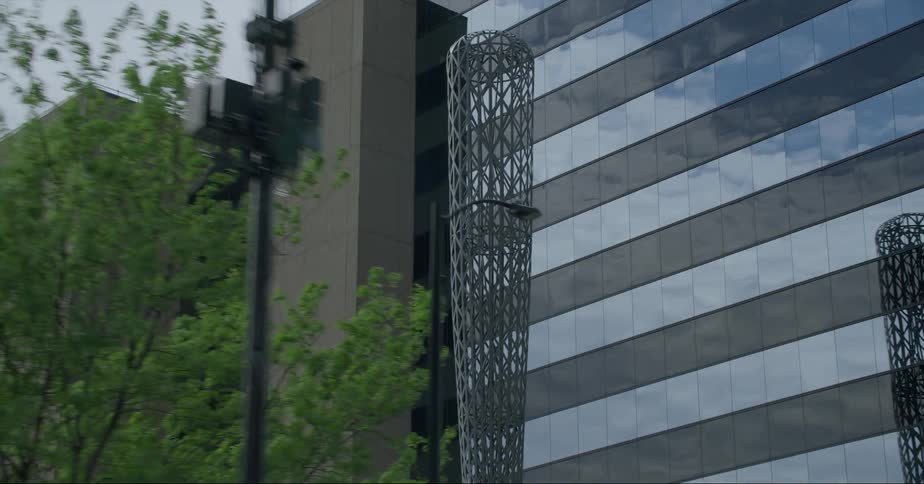 The batcolumn sculpture in chicago is reflected on a building facade on a cloudy day