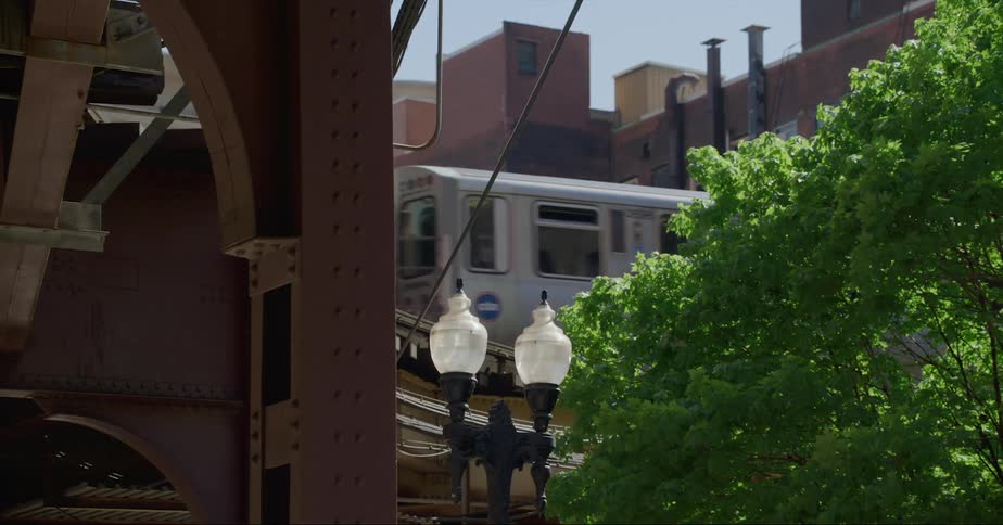 Metro train driving on an elevated track over the city street at morning