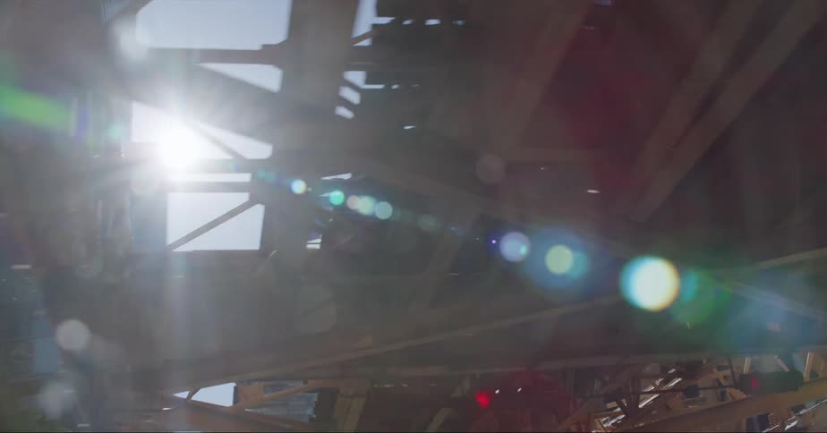 Train crosses elevated track through downtown as sun glares through the structure