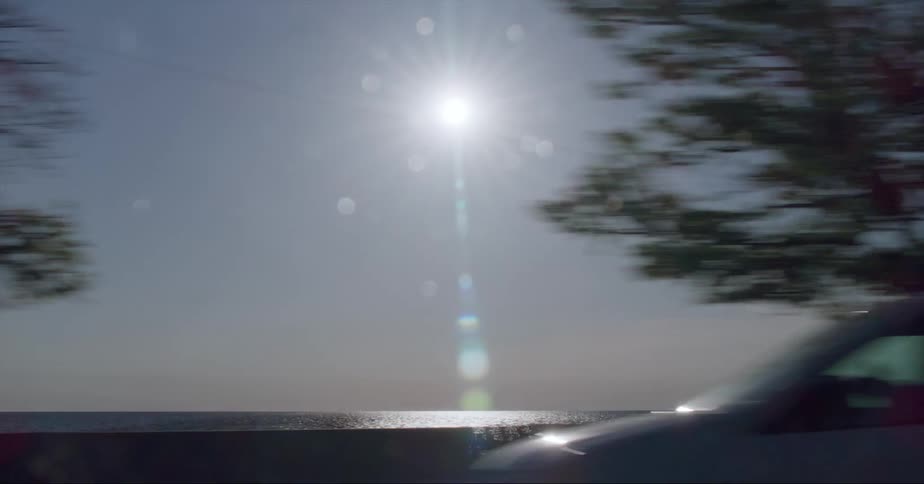 Sun shines over the calm surface of lake michigan seen from a moving vehicle in the afternoon