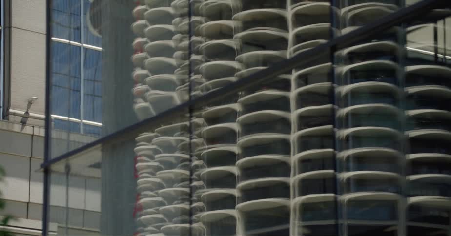 City skyline reflects on the glass facade of a skyscraper at daytime