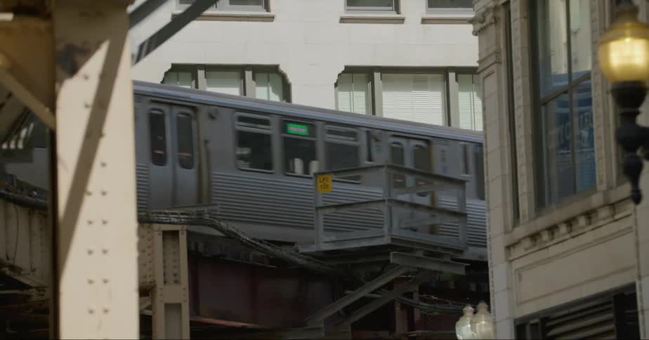 Metro train driving on an elevated track over the city street at morning