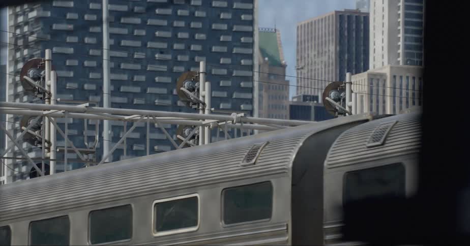 Train parked behind a wire fence next to the city skyline at daytime