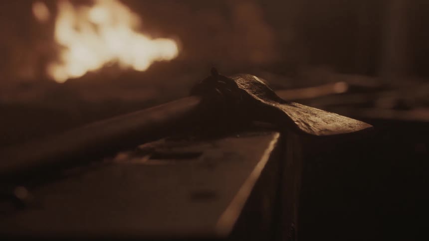 An ax sits on a table beside a large fire