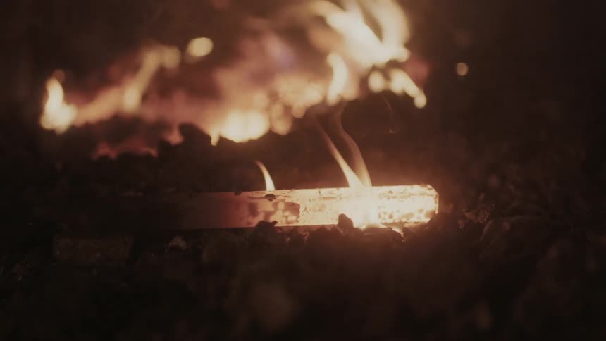 Flames licking red-hot iron as it rests on coals next to a fire