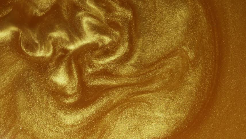 A shiny gold liquid sparkles and ripples as it spreads