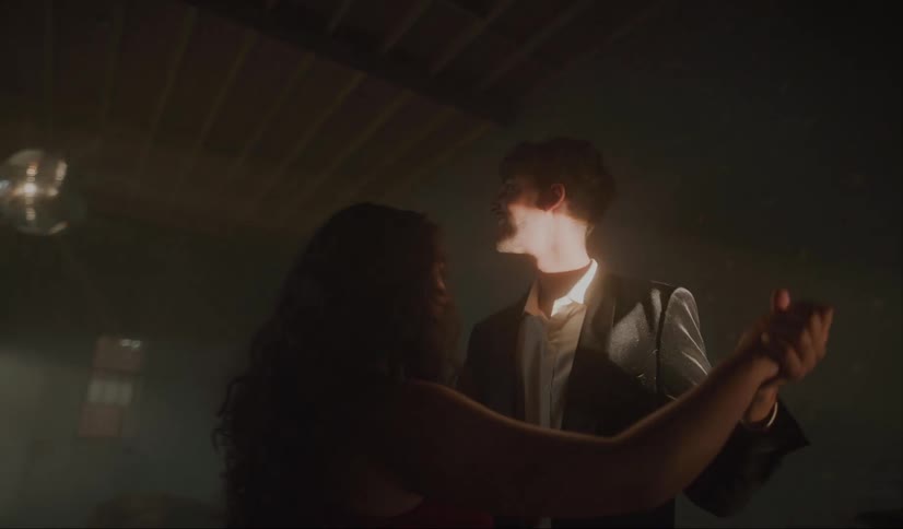 Two teens slow dancing awkwardly with a disco ball light shining on them