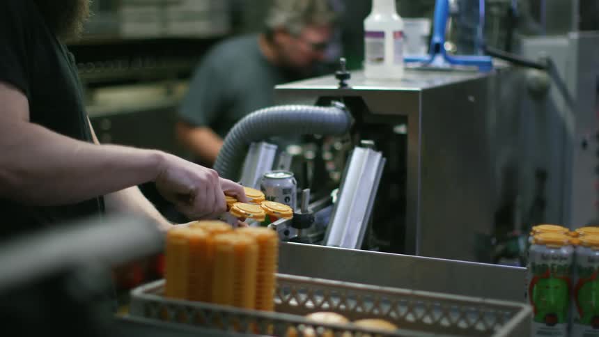 Two men are packaging cans in the factory