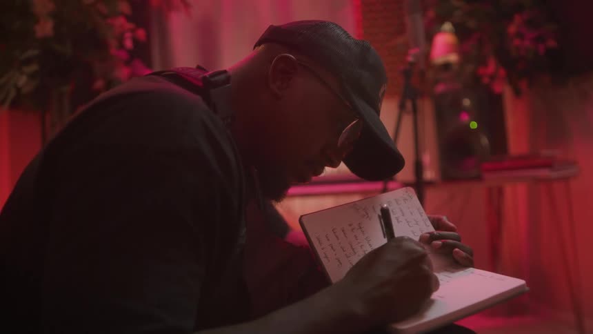 A man sits at home and writes in a notebook