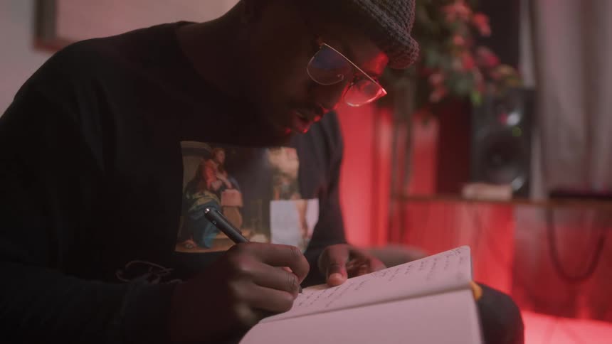 A man sits at home and writes in a notebook