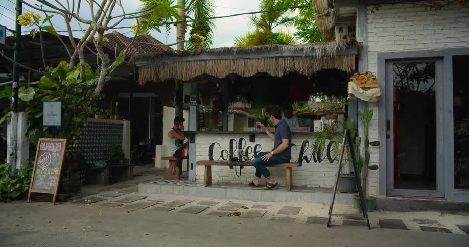 Tourist drinks a beverage on a small caf on the street of a tropical town
