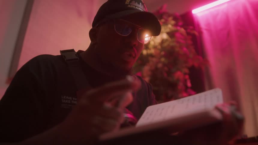 A man moves his head and fingers as he sings while writing a song