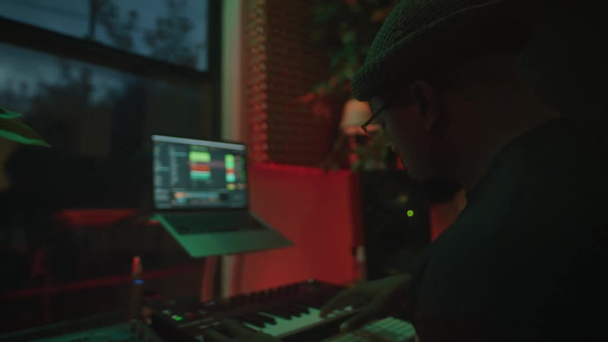 A man plays the keyboard and records it on a laptop