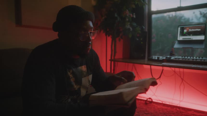 A man reads a book with sitting indoors in the evening