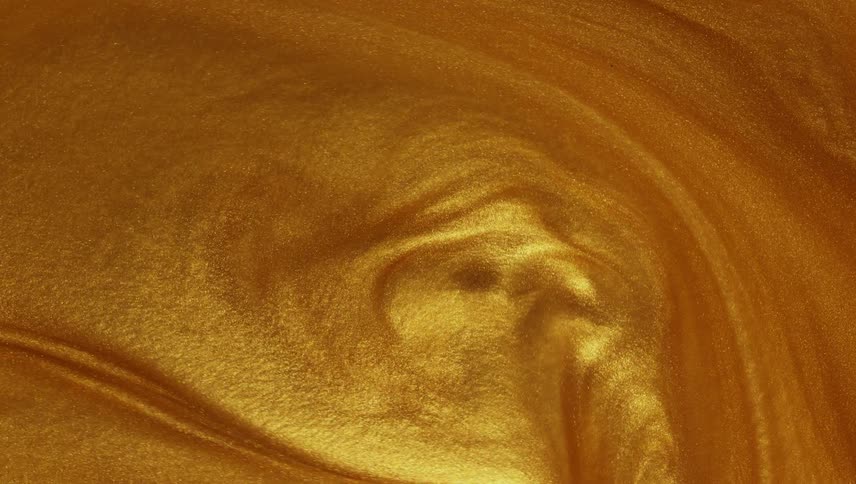 A shiny gold liquid sparkles and ripples as it swirls and spreads