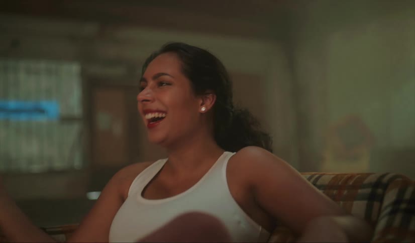 Happy handsome woman laughs and smile while sitting on a chair inside an abandoned warehouse