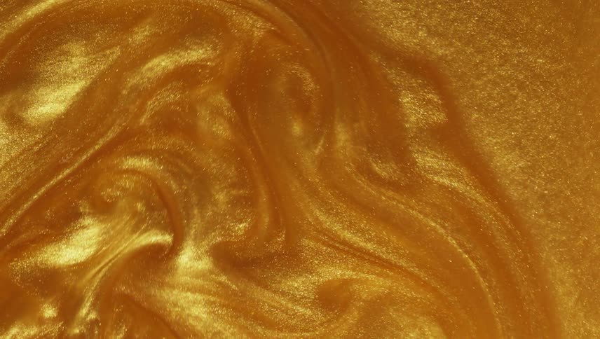 Light shines on a liquid gold substance that sparkles as it swirls and moves