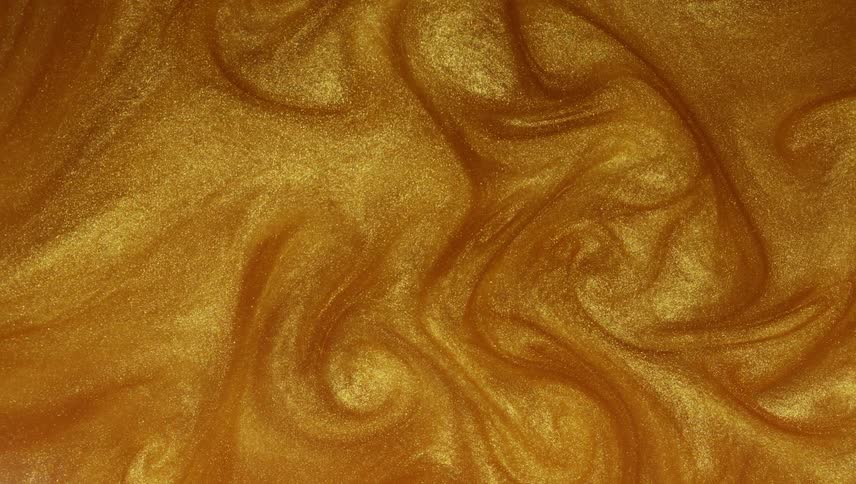 A pool of gold glittery liquid swirls around slowly creating swirl shapes and lines