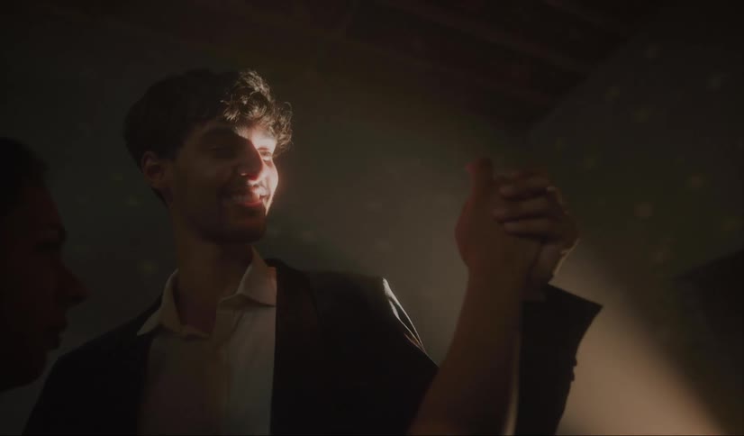 A young man looks up smiling at the shimmering light as he slow dances with his date