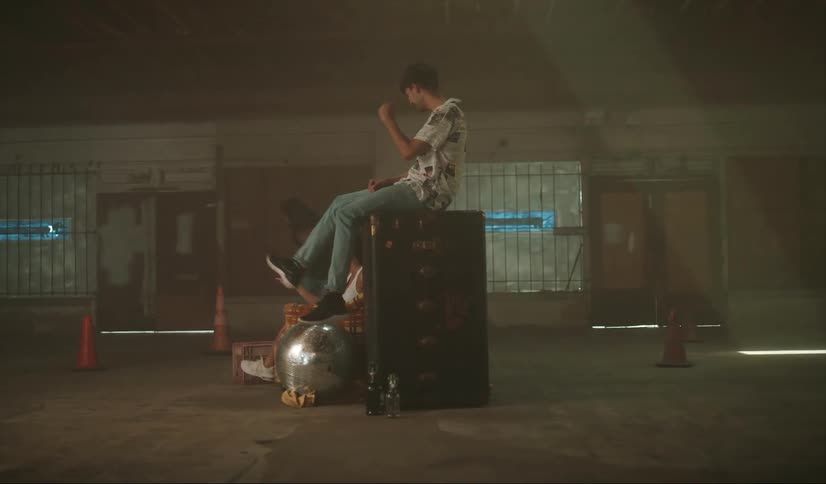 Two friends clap and cheer while skateboarders jump and do tricks in an abandoned building