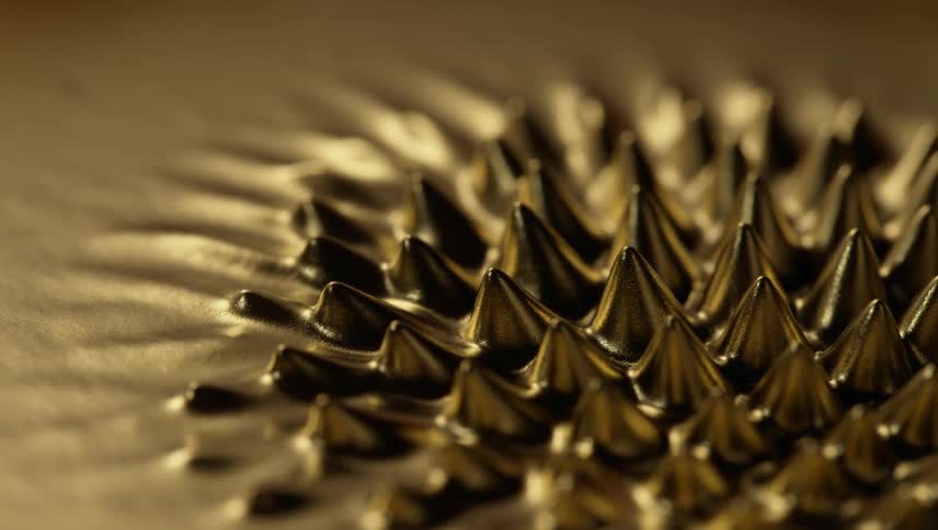 Spikes grow from a gold liquid substance and melt back down