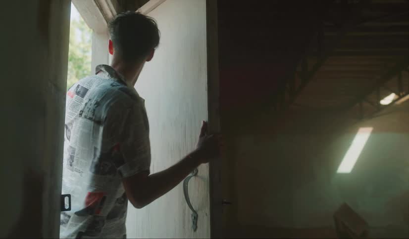 A teenage boy peeks in a door of an abandoned house and then grabs a girls hand and they run inside