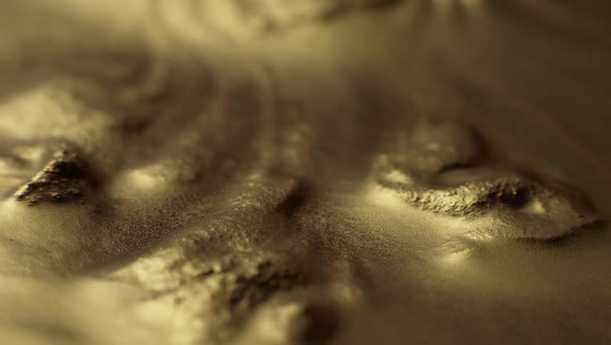 A gold liquid substance is moving as it shines flowing through lumps