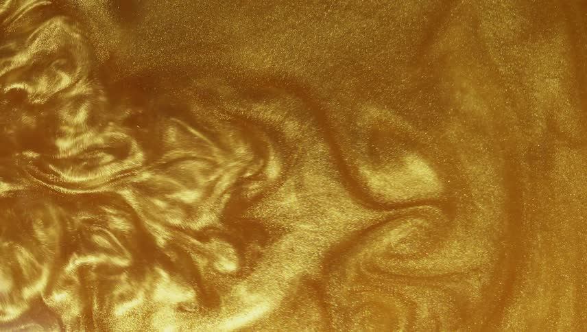 A gold liquid substance moves and ripples as it squirts outward