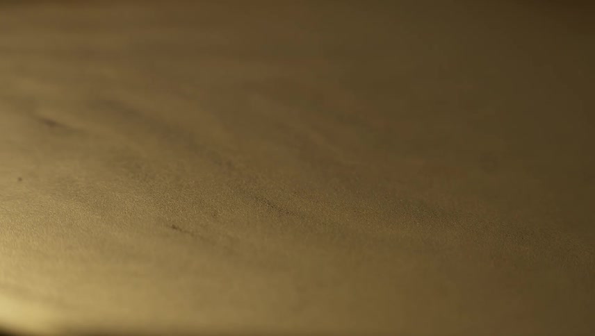 Ripples rise from a gold liquid substance and turns to spikes as they move across the surface and then melt back down